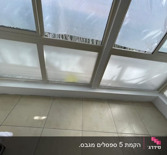 חלונות זכוכית עם מסגרות לבנות על רקע קיר גבס